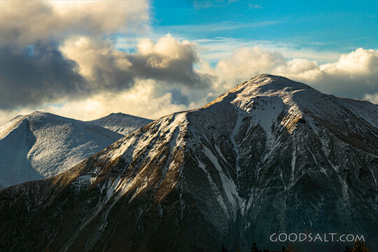Distant mountains with snow, dramatic skies.