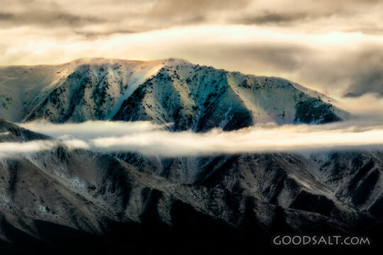 Distant mountains with snow, dramatic skies.