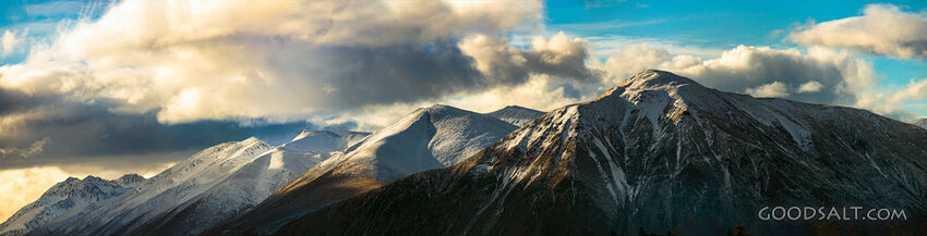Distant mountains with snow, dramatic skies.