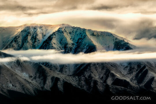 Distant mountains with snow, dramatic skies.