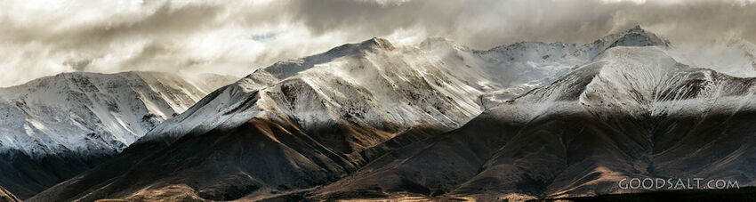 Distant mountains with snow, dramatic skies.