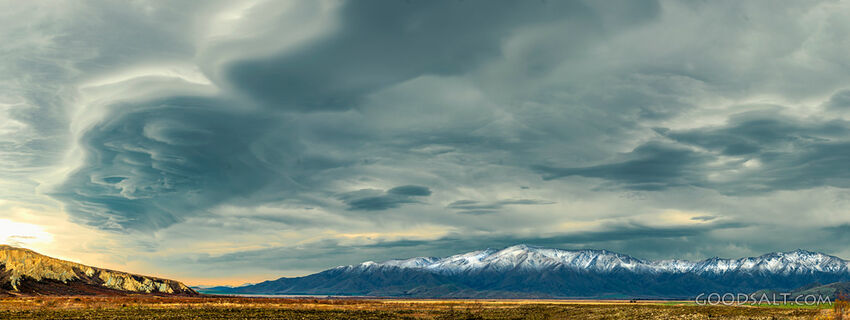Dramatic stormy Lenticular clouds sit above snowy mountains.