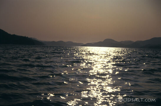 bright reflections on rippling water with mountain silhouetted horizon