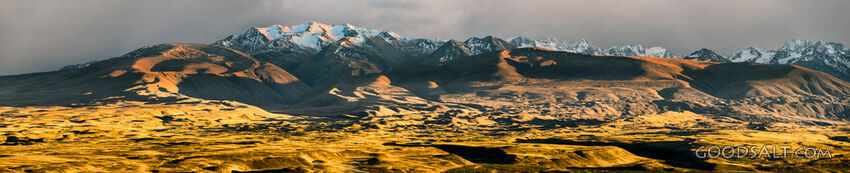 fierce early morning sun lights up yellow hilly foothills of mountain range.