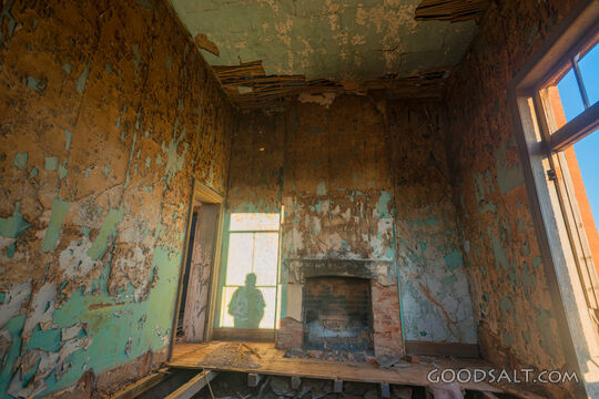 Front room interior with fireplace and peeling wall paper.