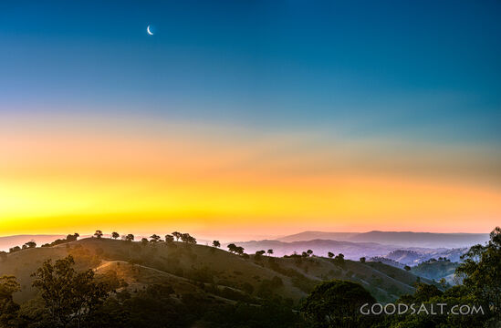 golden late sun bathes country scene and hillsides in misty light.