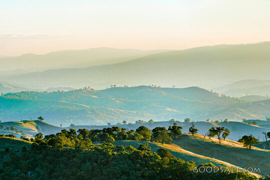 golden late sun bathes country scene and hillsides in misty light.