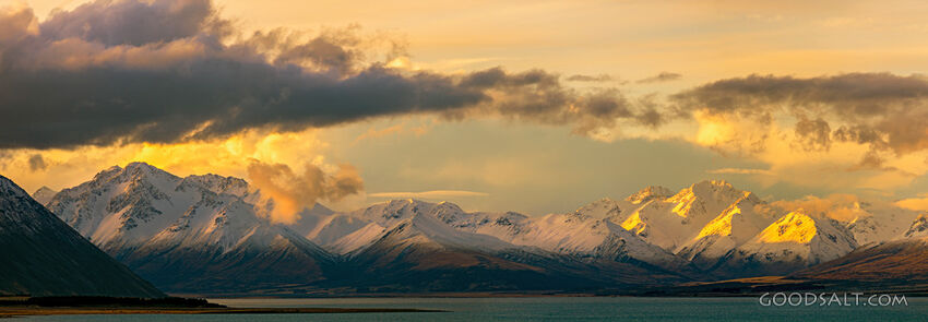 Golden lit peaks on the side of a lake.