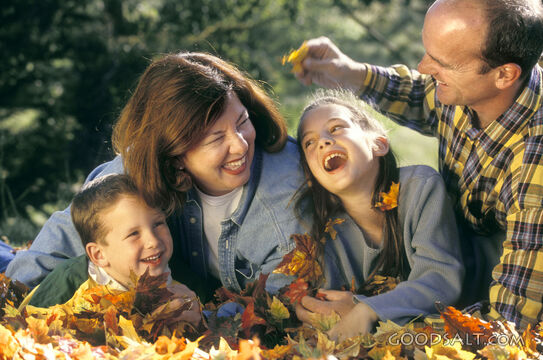 A family playing in the leaves.