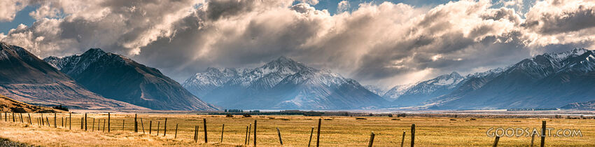 Old fence in front of mountain range with sunrays.