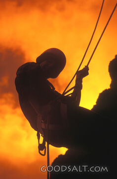A blazing sunset with the silhouette of a person climbing a rock.