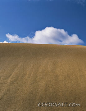 sand dune with blue sky and fluffy clouds