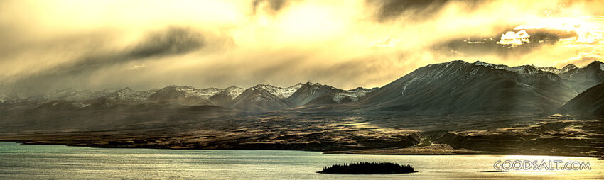 Spectacular sunrise clouds over rugged remote lake and mountains.