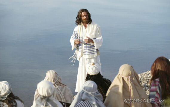 Jesus preaching to a crowd with the ocean in the background.