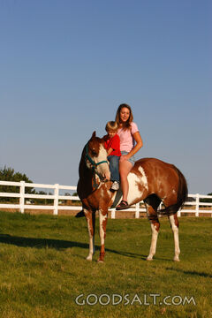 Woman and little boy riding red American Paint Horse in summ