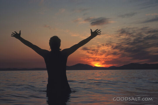 A child raising his arms and playing in the ocean.