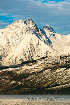 Bright morning sun on side of mountains with low cloud.