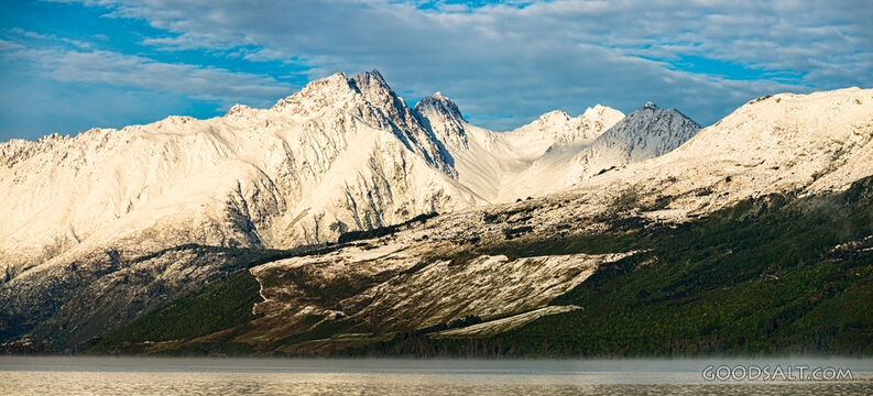 Bright morning sun on side of mountains with low cloud.