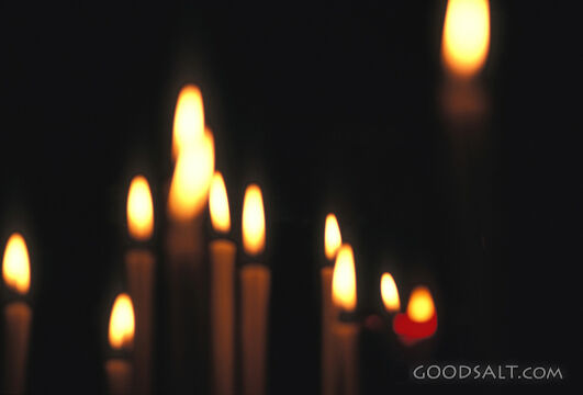 Multiple lit candles in a dark room.