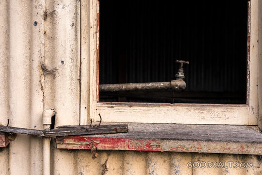 close-up of decayed window and tap on old shed