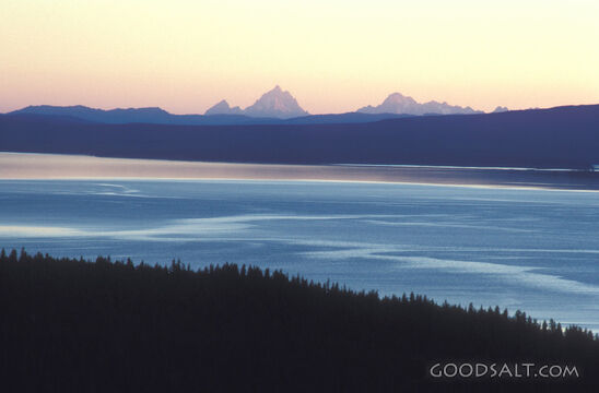 A calm ocean with large mountains in the distance.