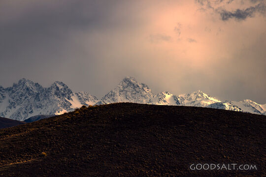 Distant mountains before dawn behind dark hill.