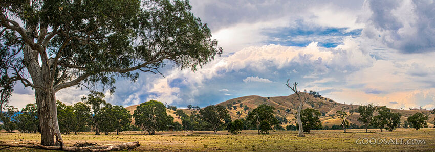 Farm hills and infrastructure in green hilly land with dramatic sky.