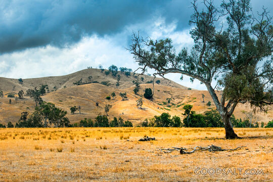Farm hills and infrastructure in green hilly land with dramatic sky.