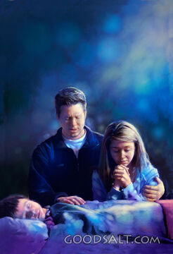 Father and Mother Pray over Sleeping Son