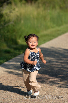 Happy little girl running on sidewalk.