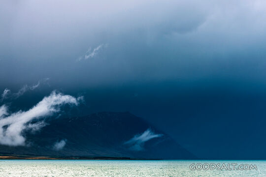 Heavy dark sky behind yellow clay cliffs.
