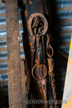Horse and harness gear hanging on old post.