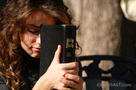 IDAHO. Boise. Young woman holding Bible and praying outdoors