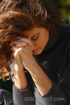 IDAHO. Boise. Young woman praying with face hidden (close-up