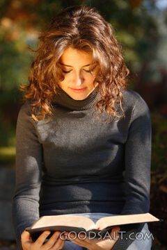 IDAHO. Boise. Young woman reading Bible outdoors (close-up).