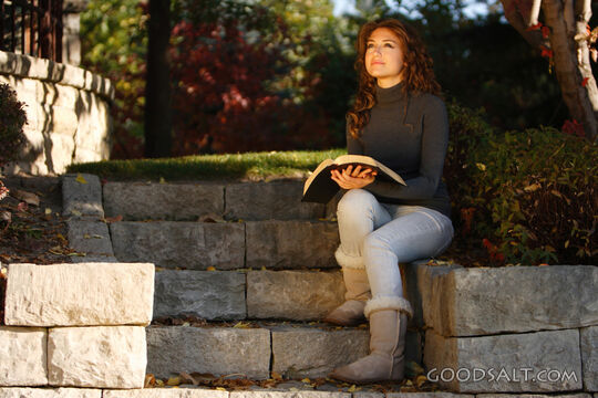 IDAHO. Boise. Young woman reading Bible outdoors (close-up).