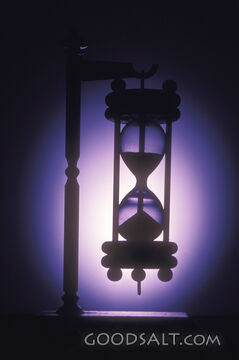 A small hourglass with a lavender light shining around it.