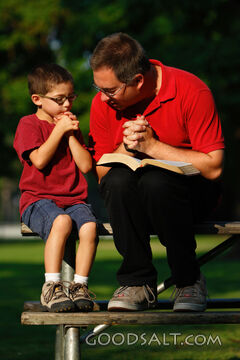 Man and little boy praying outdoors in summer.