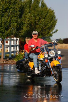 Man and little boy riding Harley motorcycle outdoors in summ