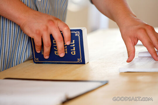 Man’s hands holding Hebrew prayer book.