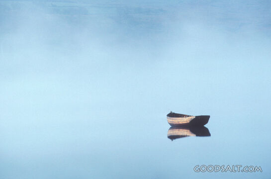 A small, empty boat floating in misty waters.