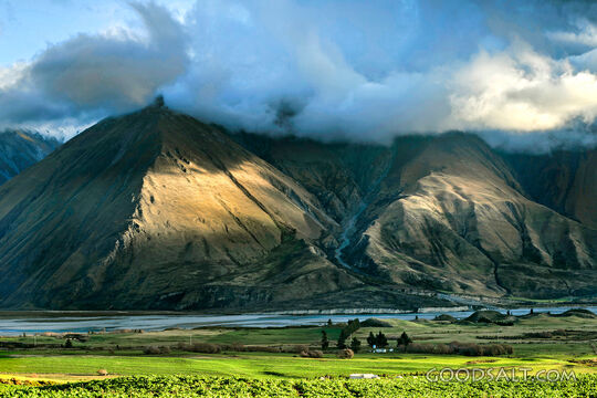 mountain range with green foreground and dramatic lighting