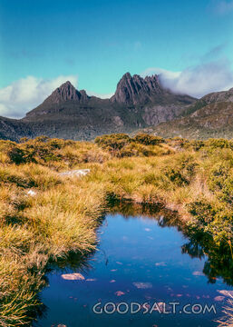 Sharp rugged peaks of mountain reflected in local tarn water.