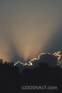 Rays of light shining from behind dark clouds.