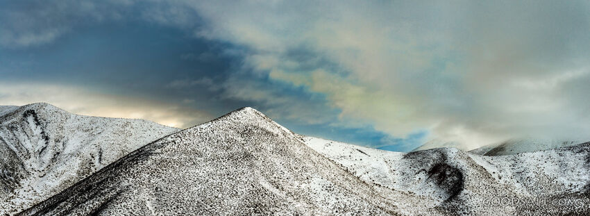 Snow covered mountain range with dramatic sky.