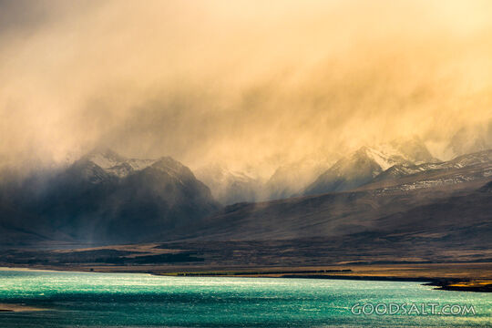 Spectacular sunrise clouds over rugged remote lake and mountains.
