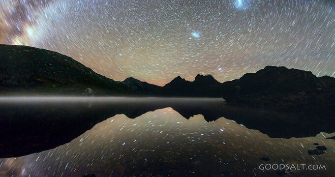 Still reflective lake and mist under the stars at night.