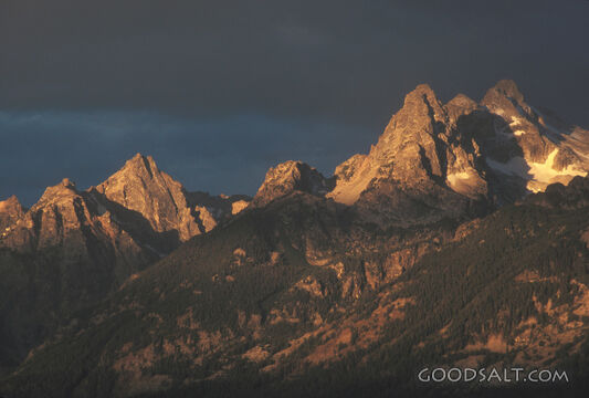 A group of mountains in a cloudy sunrise.