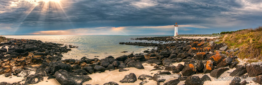 White lighthouse against a dramatic sunrise sky.