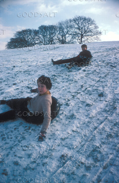 Children Sledding on a Snowy Hill